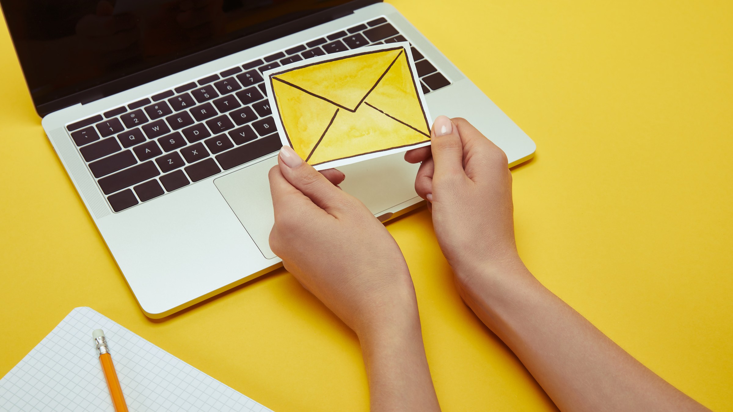 Hands typing a cold email on a laptop with an envelope graphic