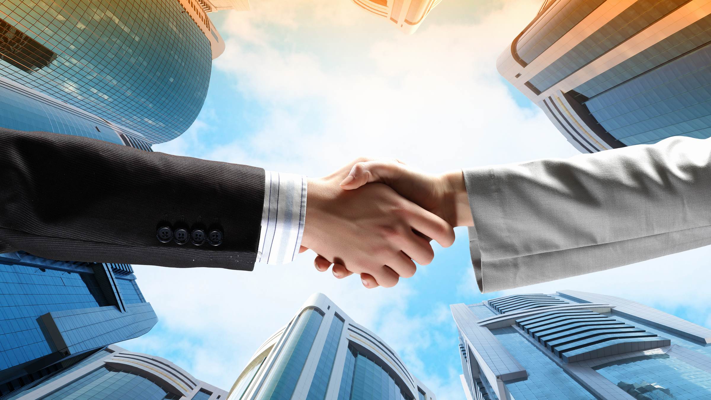 Business handshake against glass office towers, B2B prospecting