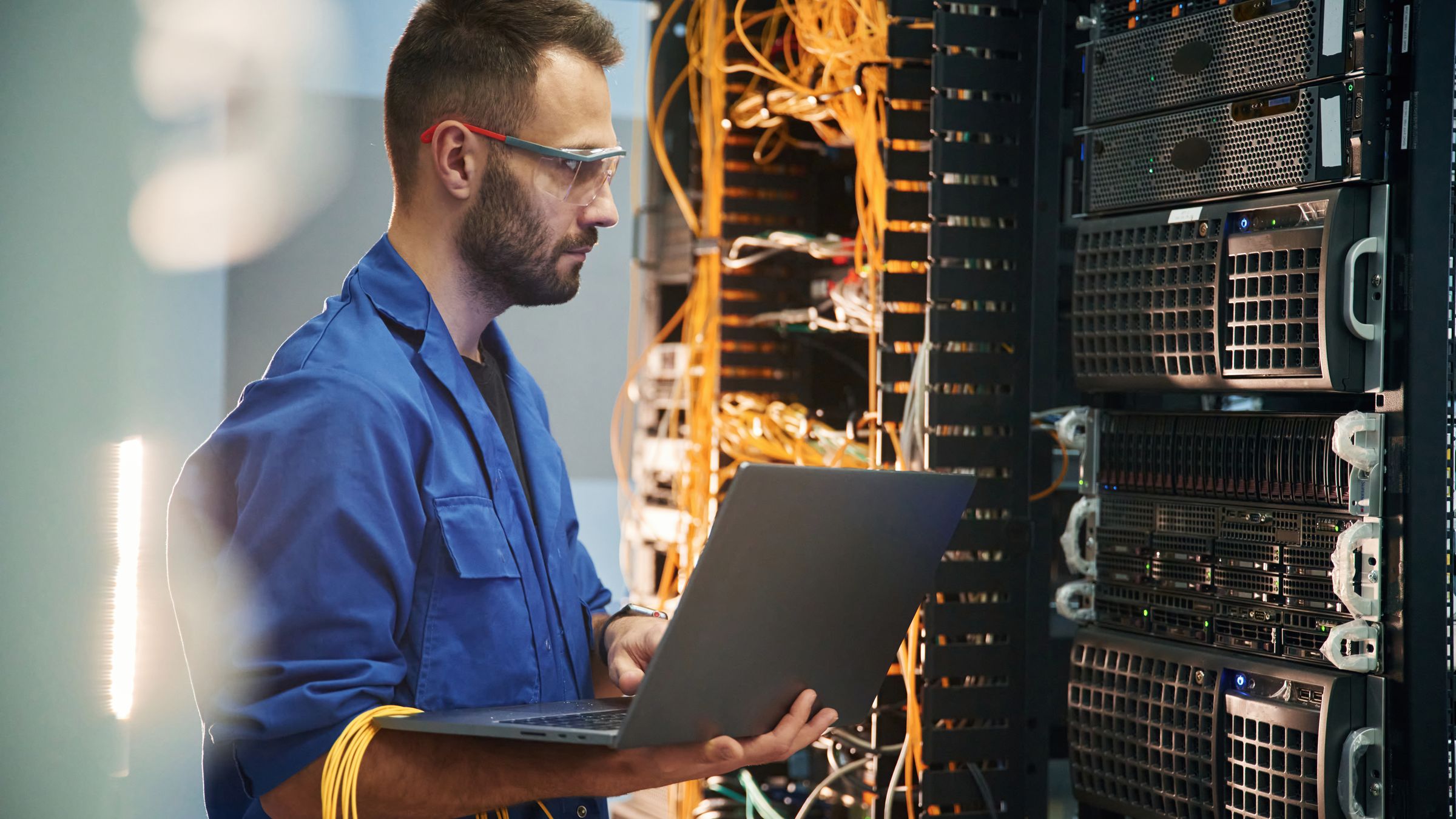 Engineer with a laptop working between data center server racks